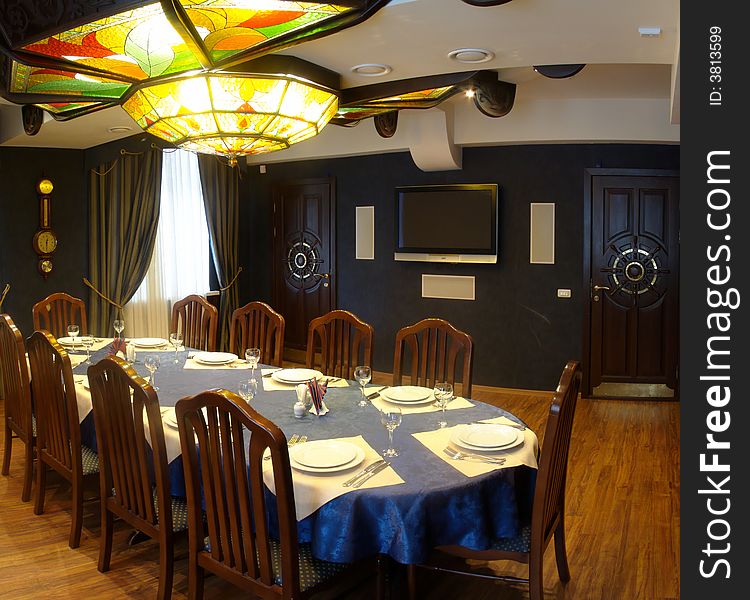 Lunch room with a large chandeliers. Chandeliers made of colored glass. Hall without bright. Cozy. In dark tones.