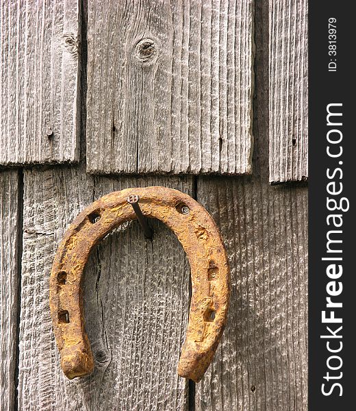 Rusty dry horseshoe pin on a nail at old wood tiles background. Rusty dry horseshoe pin on a nail at old wood tiles background