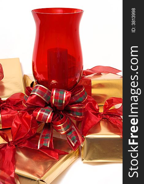 Wrapped Gifts, in red and gold, sit at a ruby red candle. Wrapped Gifts, in red and gold, sit at a ruby red candle.