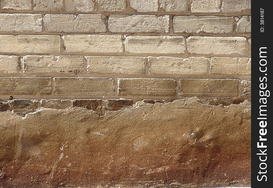Exposed brick wall behind an eroded cement overlay