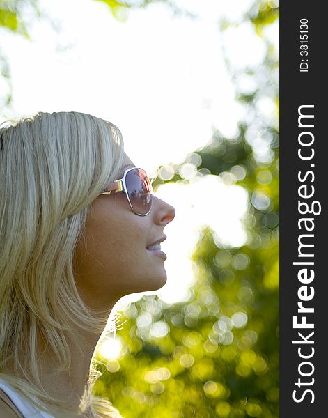 Young blond woman with sunglasses in park on summer day