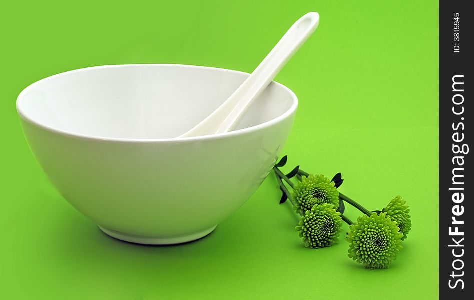 White bowl with the spoon with green flowers on green