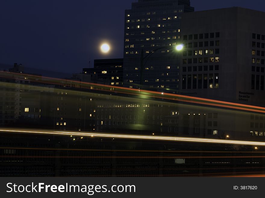 Fast moving commuter train leaves a red streak beneath the rising moon. Fast moving commuter train leaves a red streak beneath the rising moon