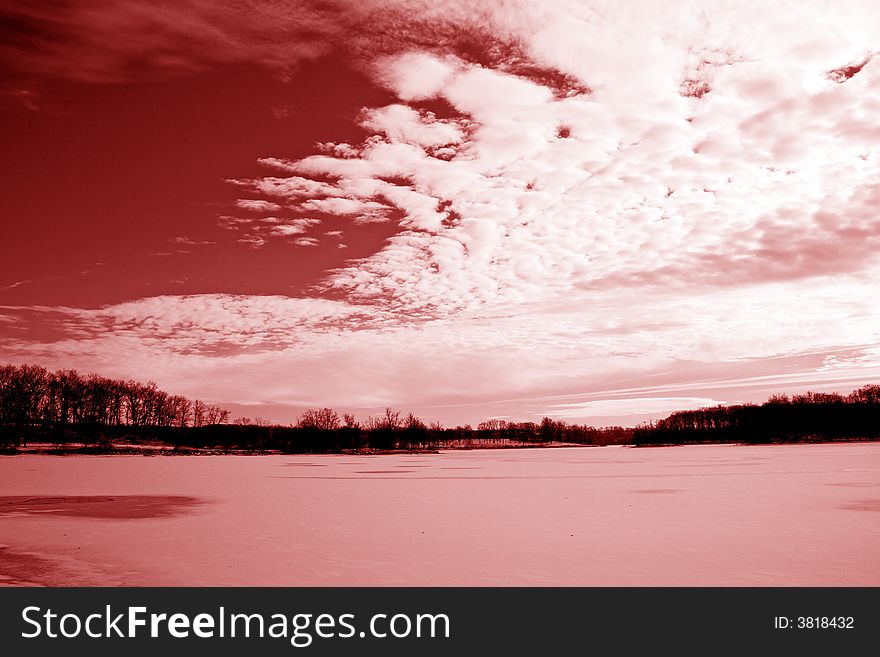 Red sky with white clouds covering over a frozen lake. Red sky with white clouds covering over a frozen lake.