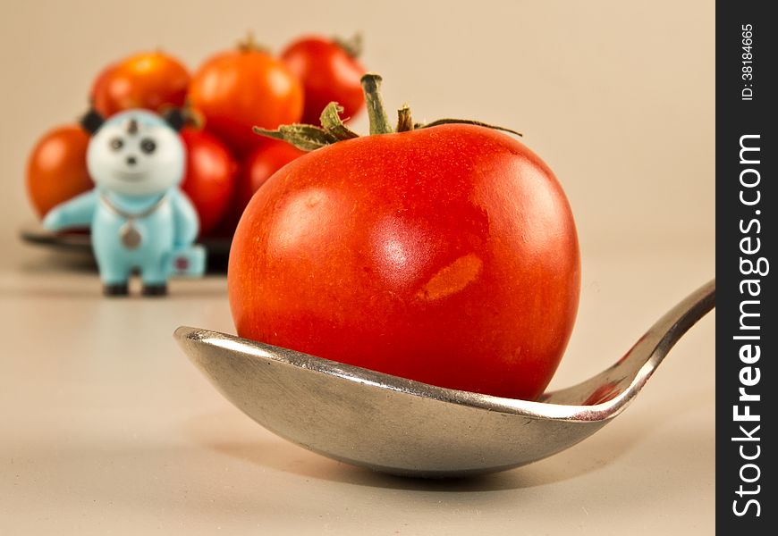 Healthy Tomato diet, doctor standing in background. Tomato in spoon. An Tomato a day keeps doctor away!. Healthy Tomato diet, doctor standing in background. Tomato in spoon. An Tomato a day keeps doctor away!