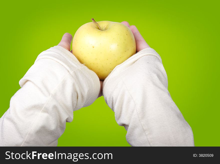 Female hands holding a yellow apple on a green background. Female hands holding a yellow apple on a green background.