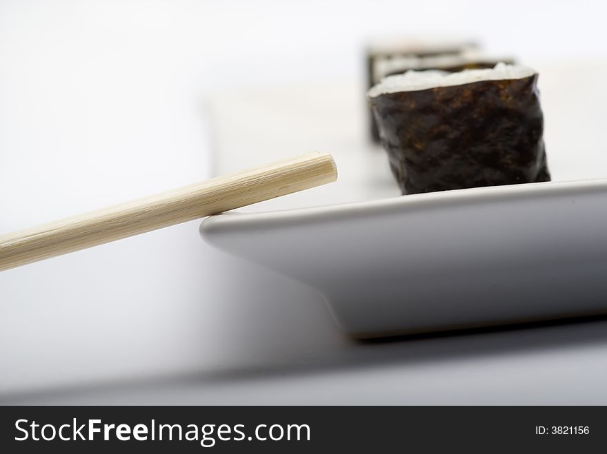 Composition of maki sushi, white late and a stick. Close focus and shallow depht of field used