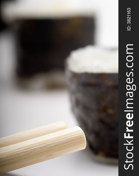 Composition of maki sushi, white late and a stick. Close focus and shallow depht of field used