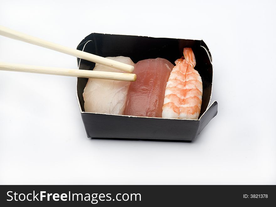 Three pieces of various nigiri in a black box with sticks. Three pieces of various nigiri in a black box with sticks.