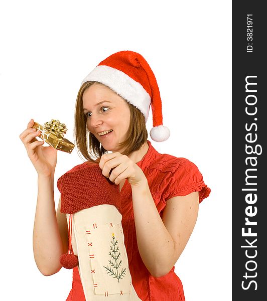 Young girl with cute smile and santa hat looking at her christmas gift in golden wrap. Young girl with cute smile and santa hat looking at her christmas gift in golden wrap