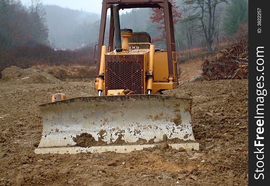 Looking at the front of a bulldozer equiped with a blade.