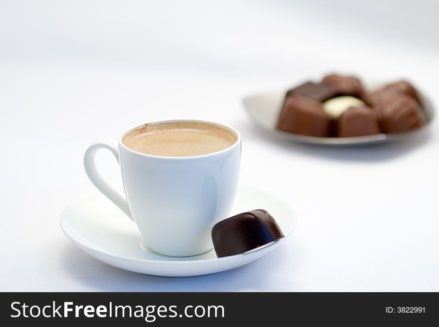 Cup of coffee with a chocolate on the background out of focus. Cup of coffee with a chocolate on the background out of focus