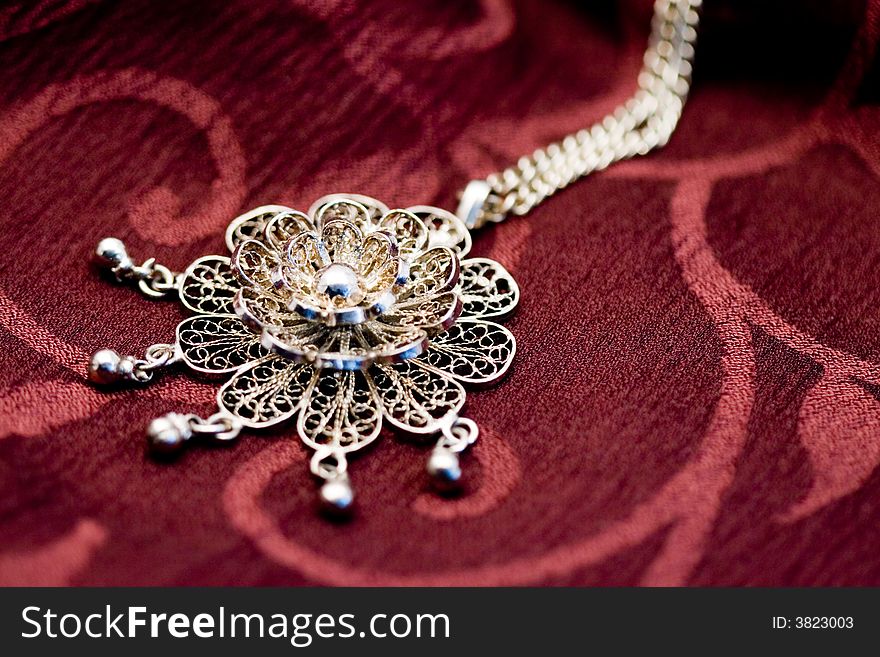 Close-up of a woman's necklace on a red surface