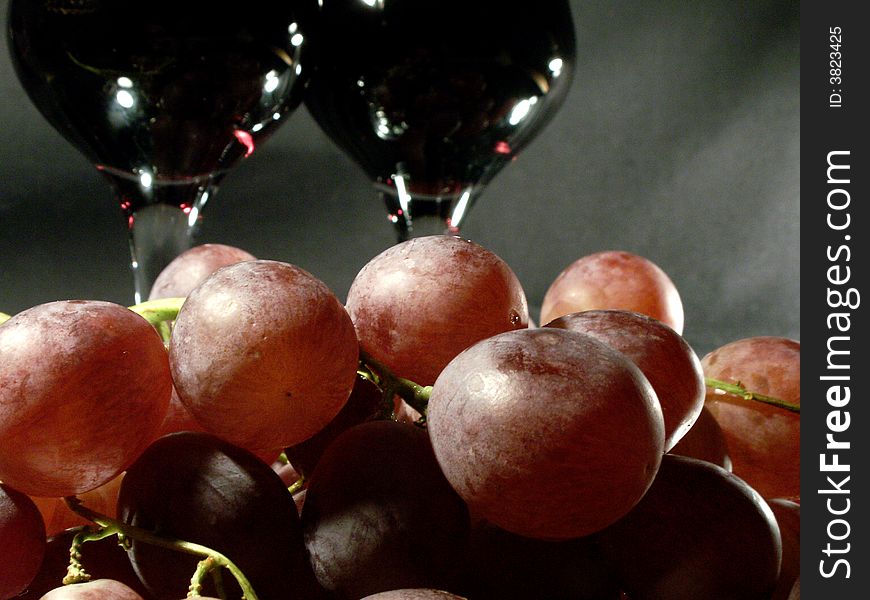 Bunch of grapes and two wineglass on dark background. Bunch of grapes and two wineglass on dark background