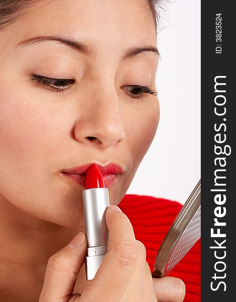 An attractive young woman applying red lipstick