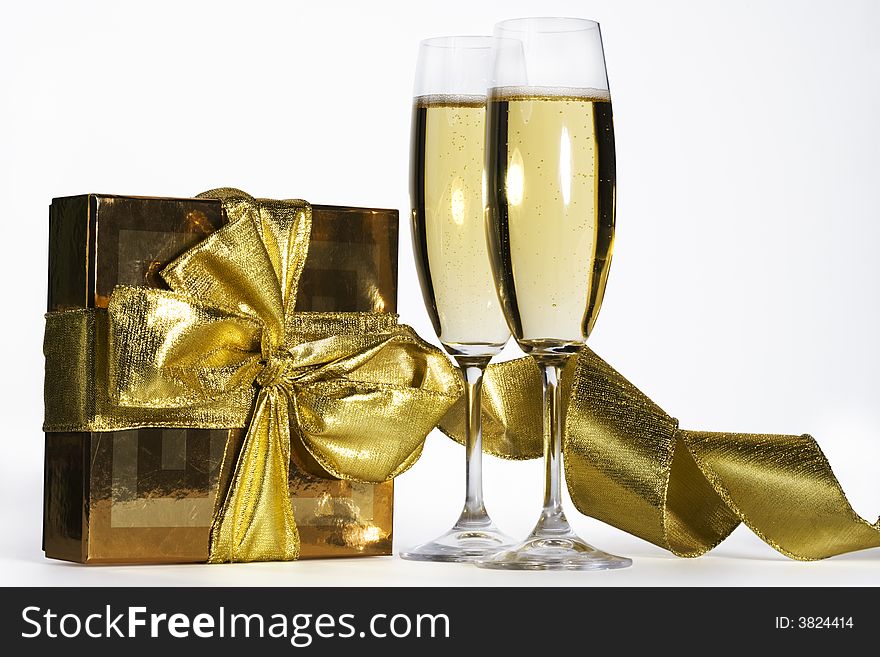 Pair of champagne flutes and golden gift box.