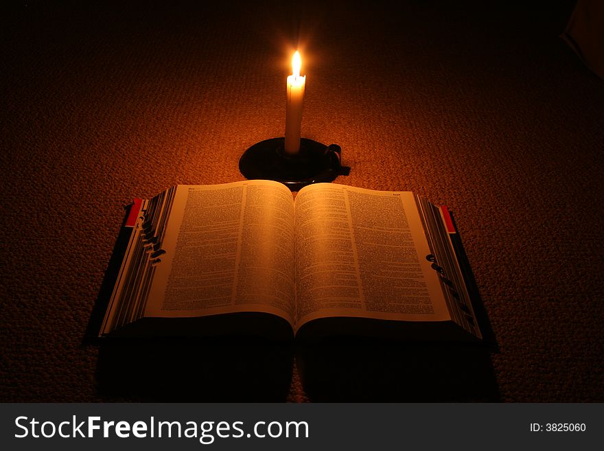 Open book in the dark with burning candle. Open book in the dark with burning candle.