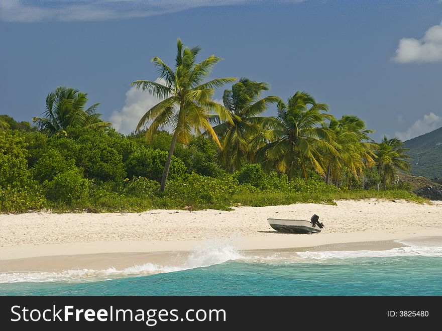 A boat alone on the beach at Sandy Cay with Tortola in the background in the British Virgin Islands BVI. A boat alone on the beach at Sandy Cay with Tortola in the background in the British Virgin Islands BVI