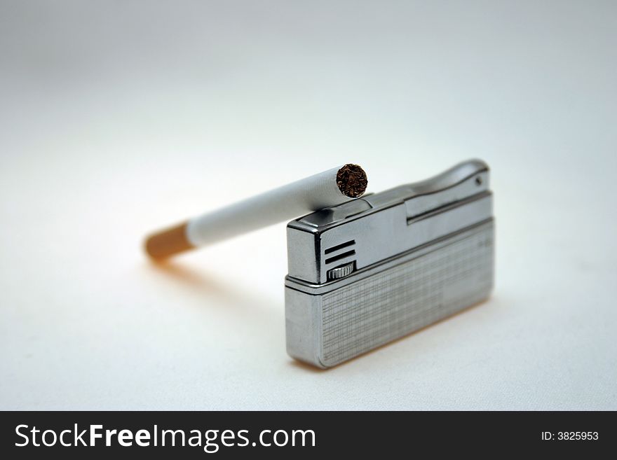 Cigarette on a lighter against a light background. Cigarette on a lighter against a light background