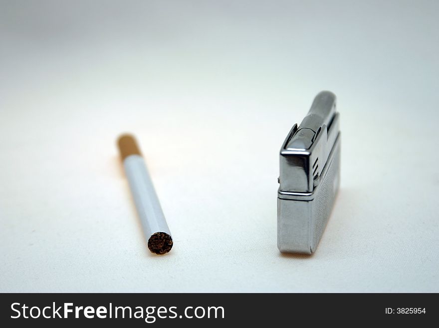 Cigarette and lighter against a light background. Cigarette and lighter against a light background