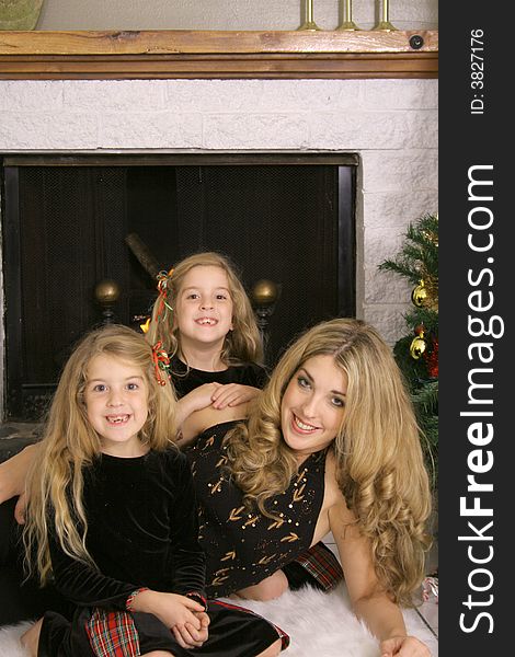 Mother with twin daughters by fireplace vertical
