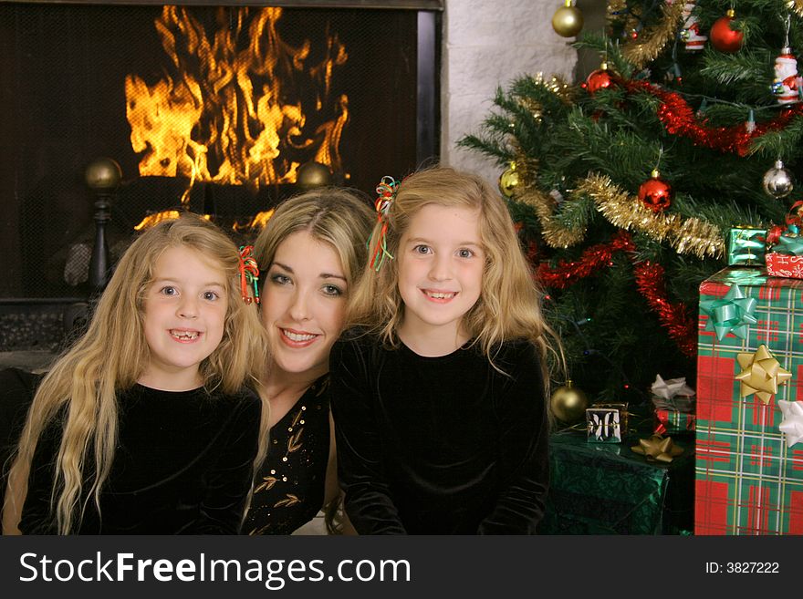 Shot of a mother with twin daughters at christmas by fireplace