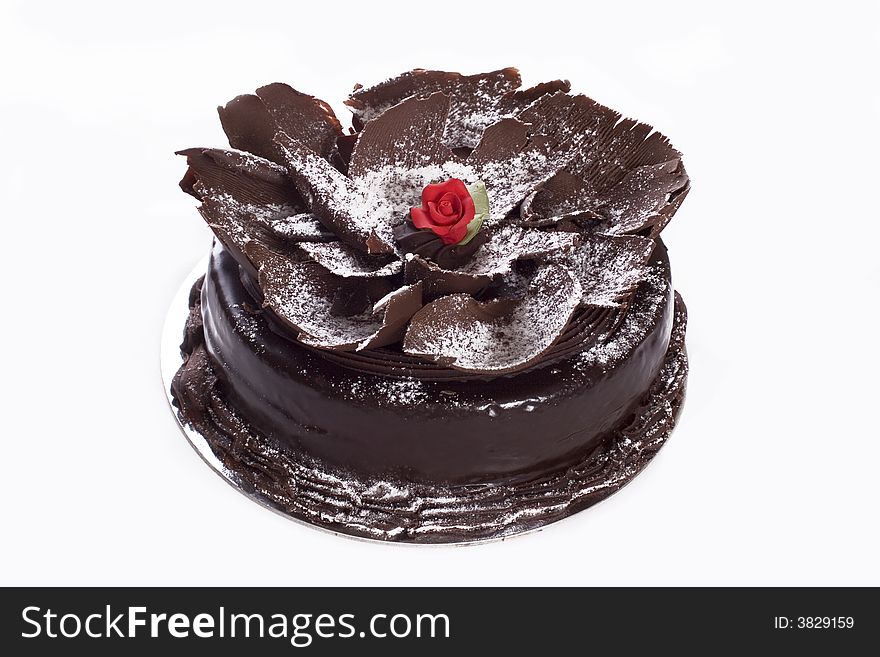Decorative chocolate cake with red rose icing center and sprinkled icing sugar on top
