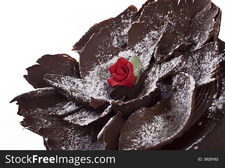 Decorative chocolate cake with red rose icing center and sprinkled icing sugar on top