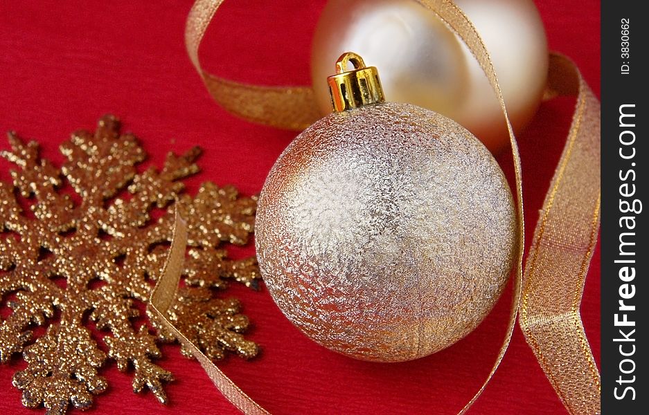 Golden christmas ornaments with a tape and a snowflake On a red background