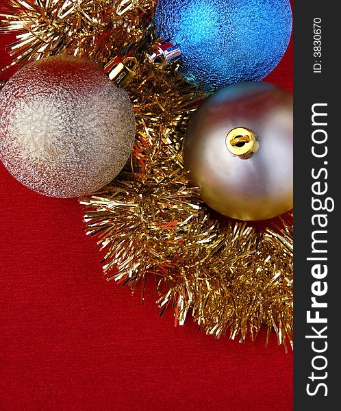 Three christmas balls with golden tinsel on red background. Three christmas balls with golden tinsel on red background