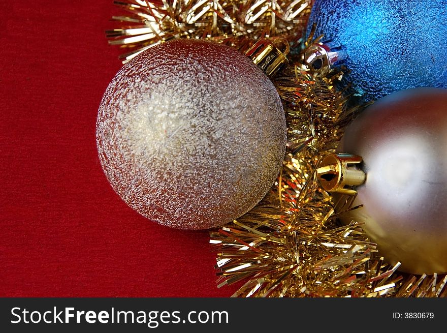 Three christmas balls with golden tinsel on red background. Three christmas balls with golden tinsel on red background