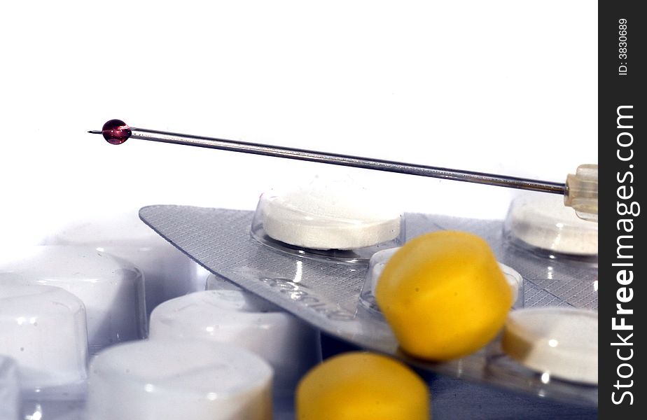 A syringe filled with liquid and different pills. Isolated over white space (for text). A syringe filled with liquid and different pills. Isolated over white space (for text).