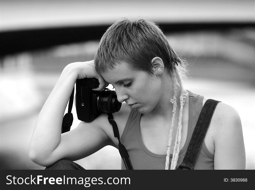 Young sad woman with a short haircut holding camera. Young sad woman with a short haircut holding camera