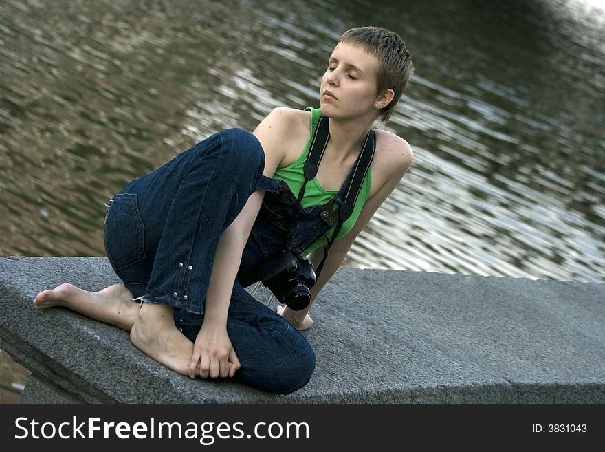 Young pretty girl with the camera resting near the river. Young pretty girl with the camera resting near the river