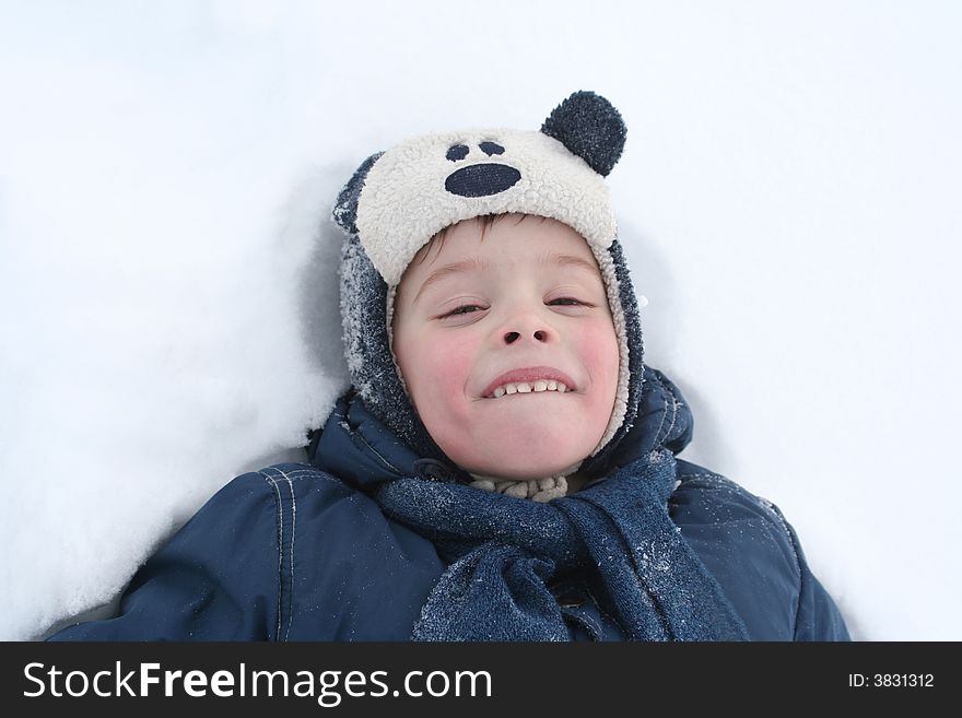 The happy boy lays in a snow