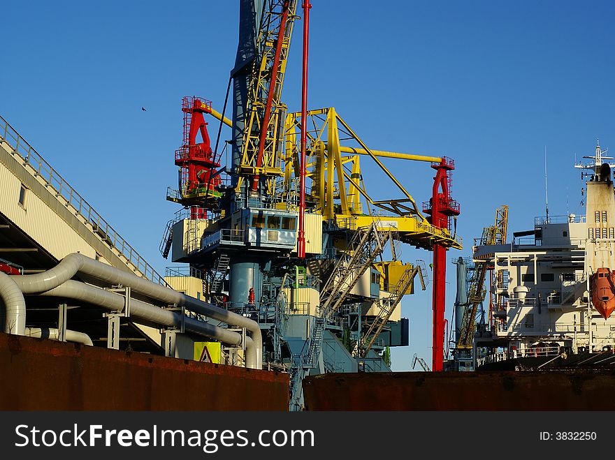 Harbor cranes and pipelines against blue sky