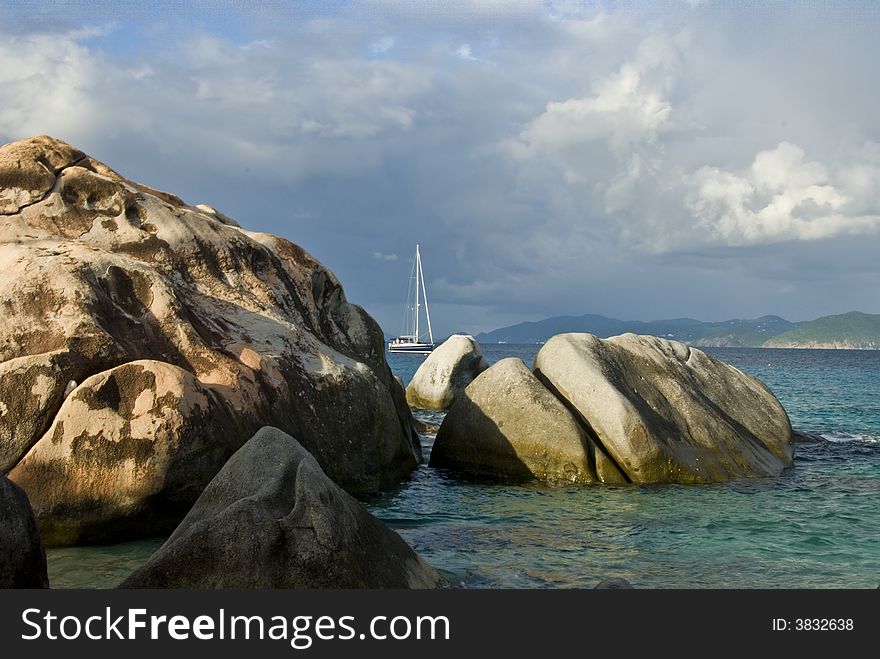 Sailboat passing the rocks at the Baths in Spanish Town on Virgin Gorda in the British Virgin Islands BVI. Sailboat passing the rocks at the Baths in Spanish Town on Virgin Gorda in the British Virgin Islands BVI