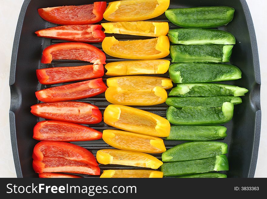Colorful rows of green, yellow and red capsicum strips prepared for cooking on a pan. Colorful rows of green, yellow and red capsicum strips prepared for cooking on a pan