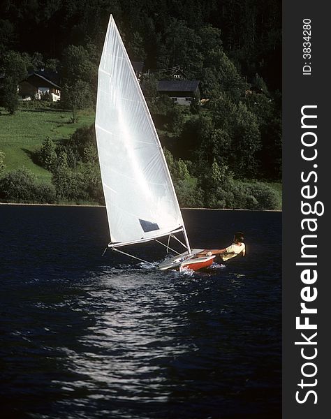 Youth handling sailboat alone on Austrian lake. Youth handling sailboat alone on Austrian lake