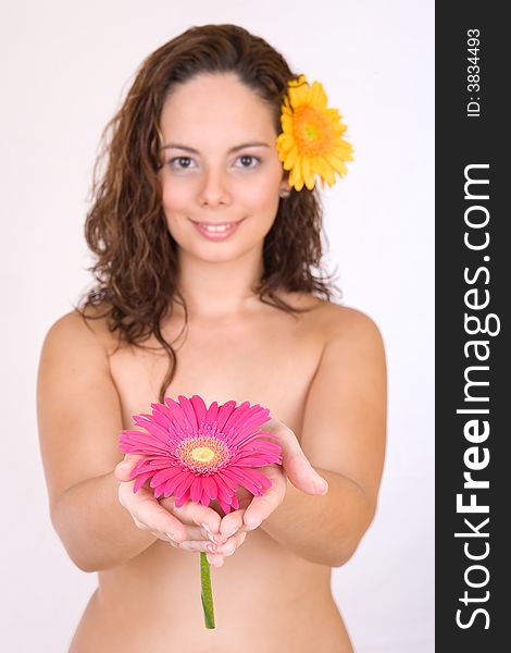 Beautiful girl with a flower in her head shows a pink flower - Beauty and Spa - over a white background