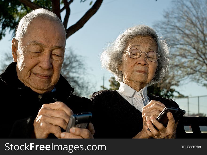 Grandma is sneaking a peak of Grandpa's handheld computer as he enters data to the device. Grandma is sneaking a peak of Grandpa's handheld computer as he enters data to the device.