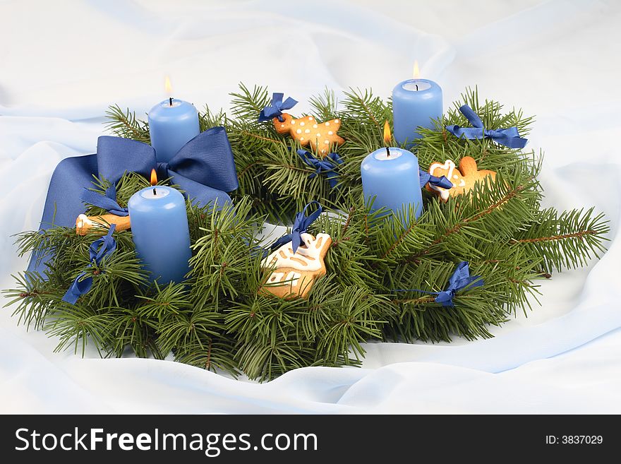 Advent wreath with blue candles, ribbon, gingerbread cookies