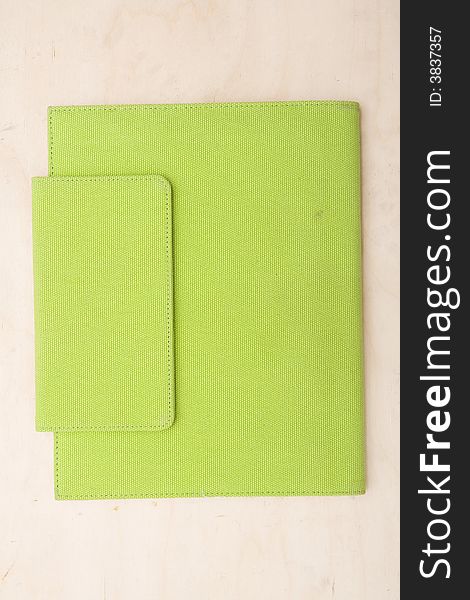 Cover of a bright lime green journal note book book photographed directly above sitting on a wood table. Cover of a bright lime green journal note book book photographed directly above sitting on a wood table.