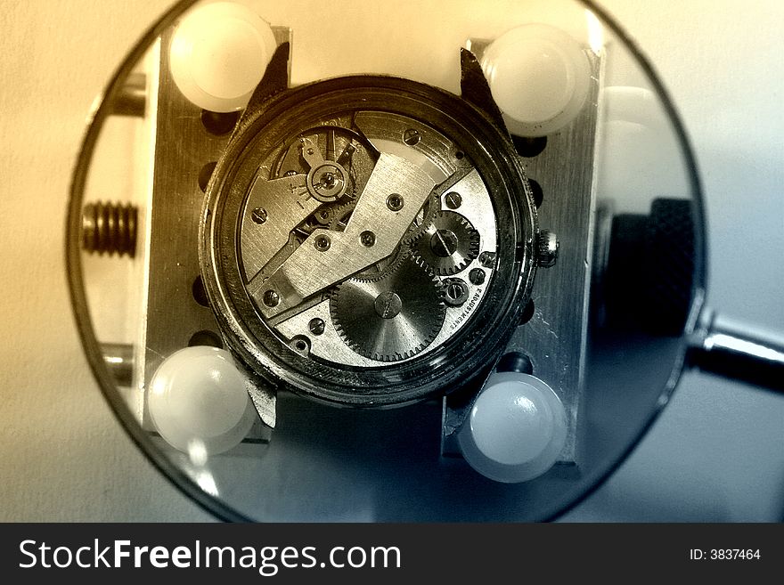 A view with a watch mechanism under a magnifier glass. A view with a watch mechanism under a magnifier glass