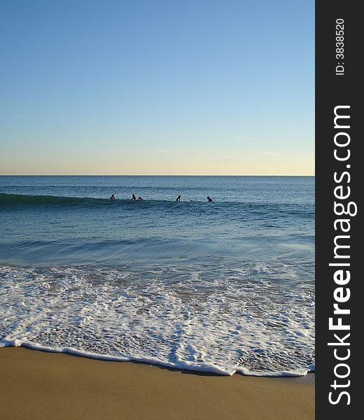 5 surfers waiting on their surfboards for the perfect wave