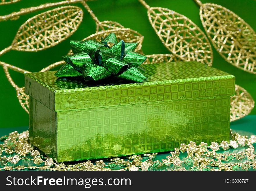 Green gift box and golden celebration leaves