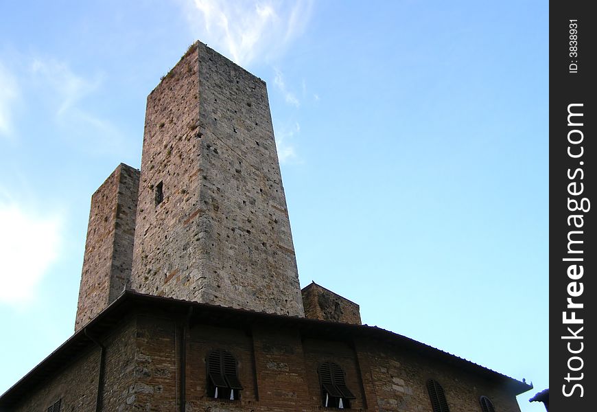 Two medieval brick towers above a palace, looking up view, dusk sky background. Two medieval brick towers above a palace, looking up view, dusk sky background
