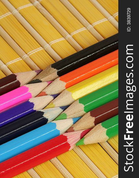 Colorful crayons on yellow bamboo mat. Colorful crayons on yellow bamboo mat