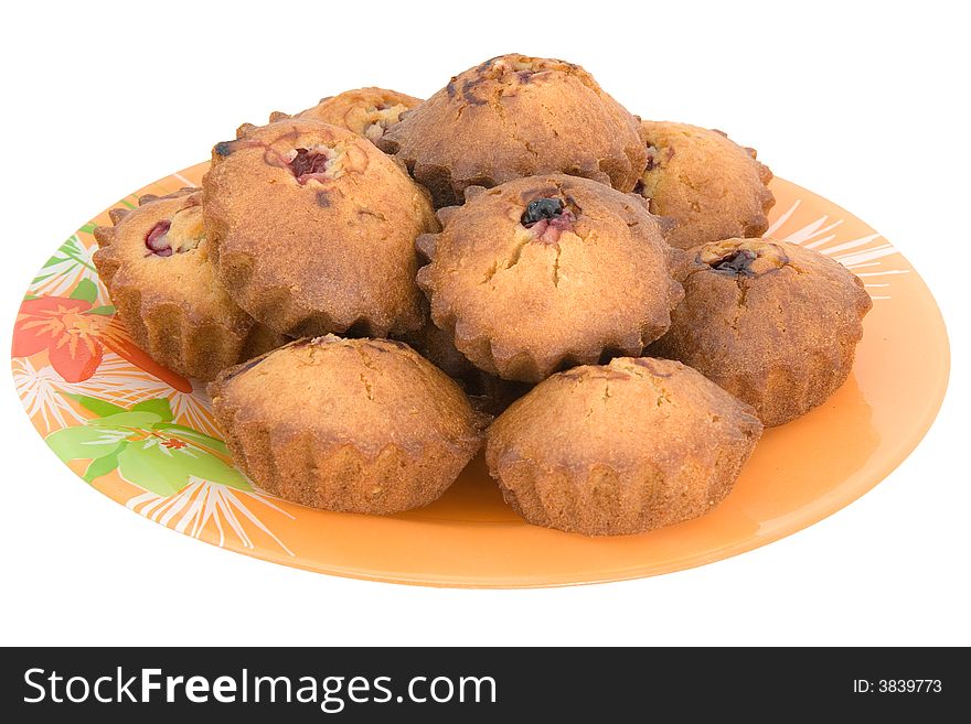 Tasty small baked cakes filled with cherry and raisins on orange round plate isolated on white. Tasty small baked cakes filled with cherry and raisins on orange round plate isolated on white