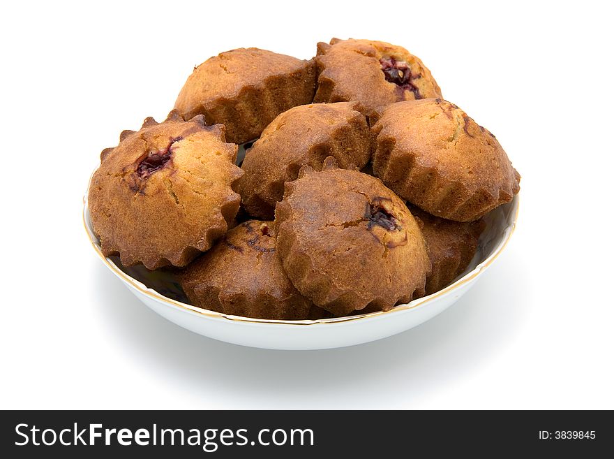 Tasty small baked cakes filled with cherry and raisins in white round bowl with shadow isolated on white. Tasty small baked cakes filled with cherry and raisins in white round bowl with shadow isolated on white